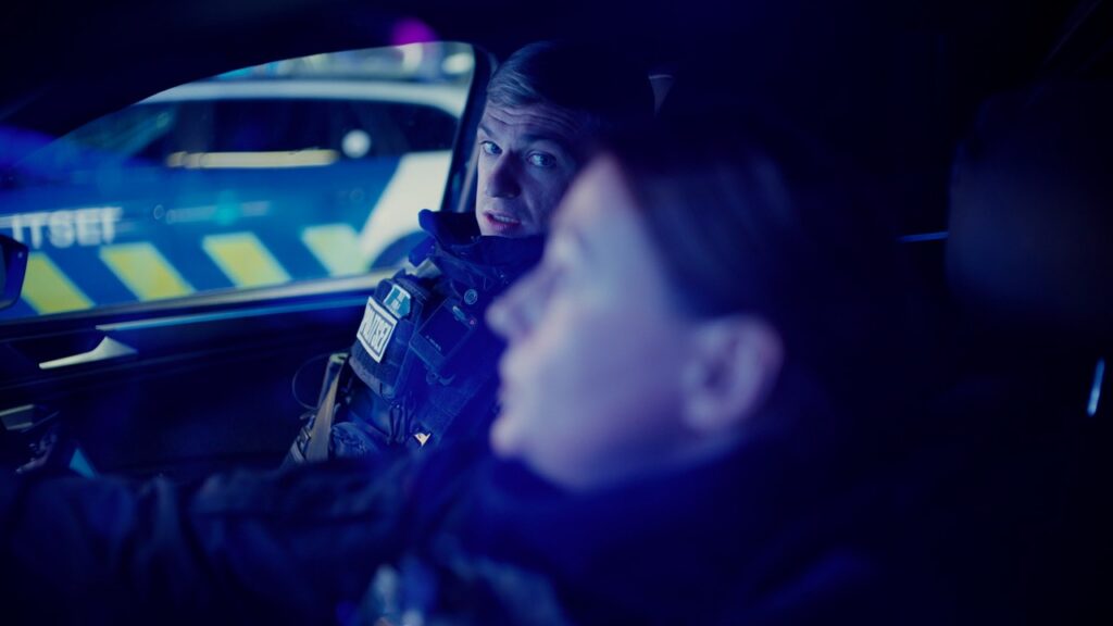 Politseinik vaatab autos enda kõrval istuvat kolleegi.