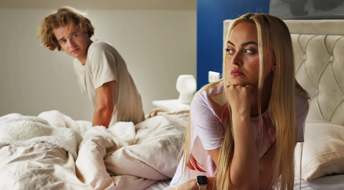 Naine istub voodil ja vaatab küljele, teisel pool voodit on mees