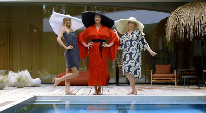 kolm naist seisavad suurte mütsidega basseini ääres