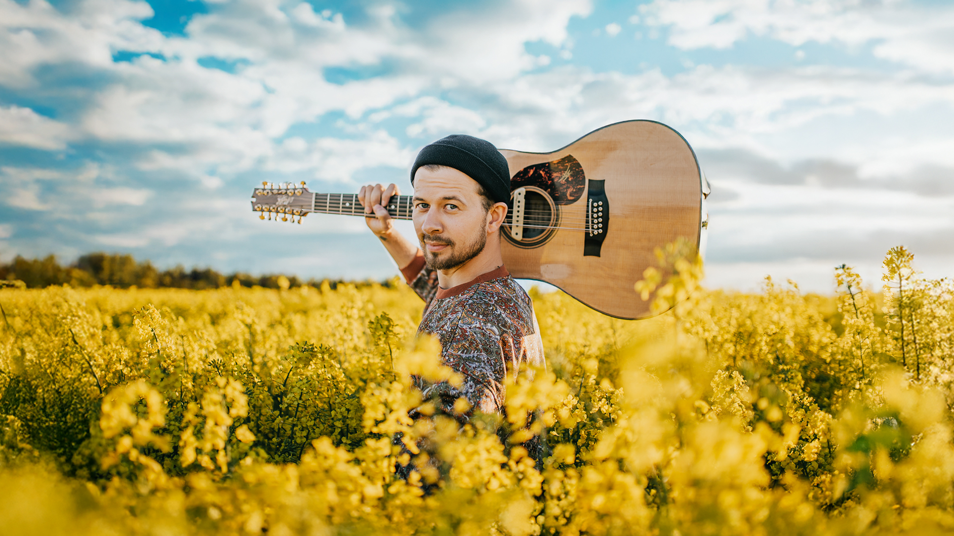 Mees seisab päevalillepõllul kitarriga